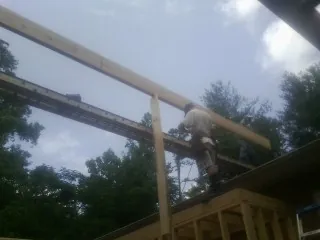 Carpenter setting a ridge beam over a new addition frame — Ice Dam Removal by Roofing Brothers in Ganado