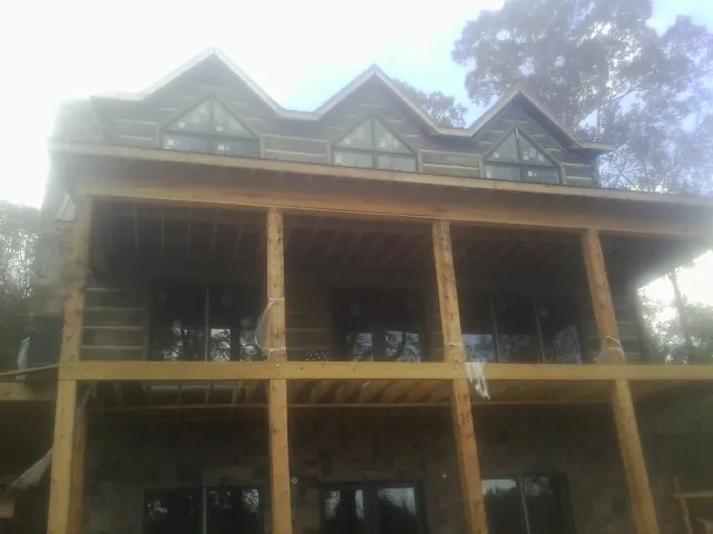 Dormers and porch framing on a large log home under construction — Roof Coating work by our crew in Ganado