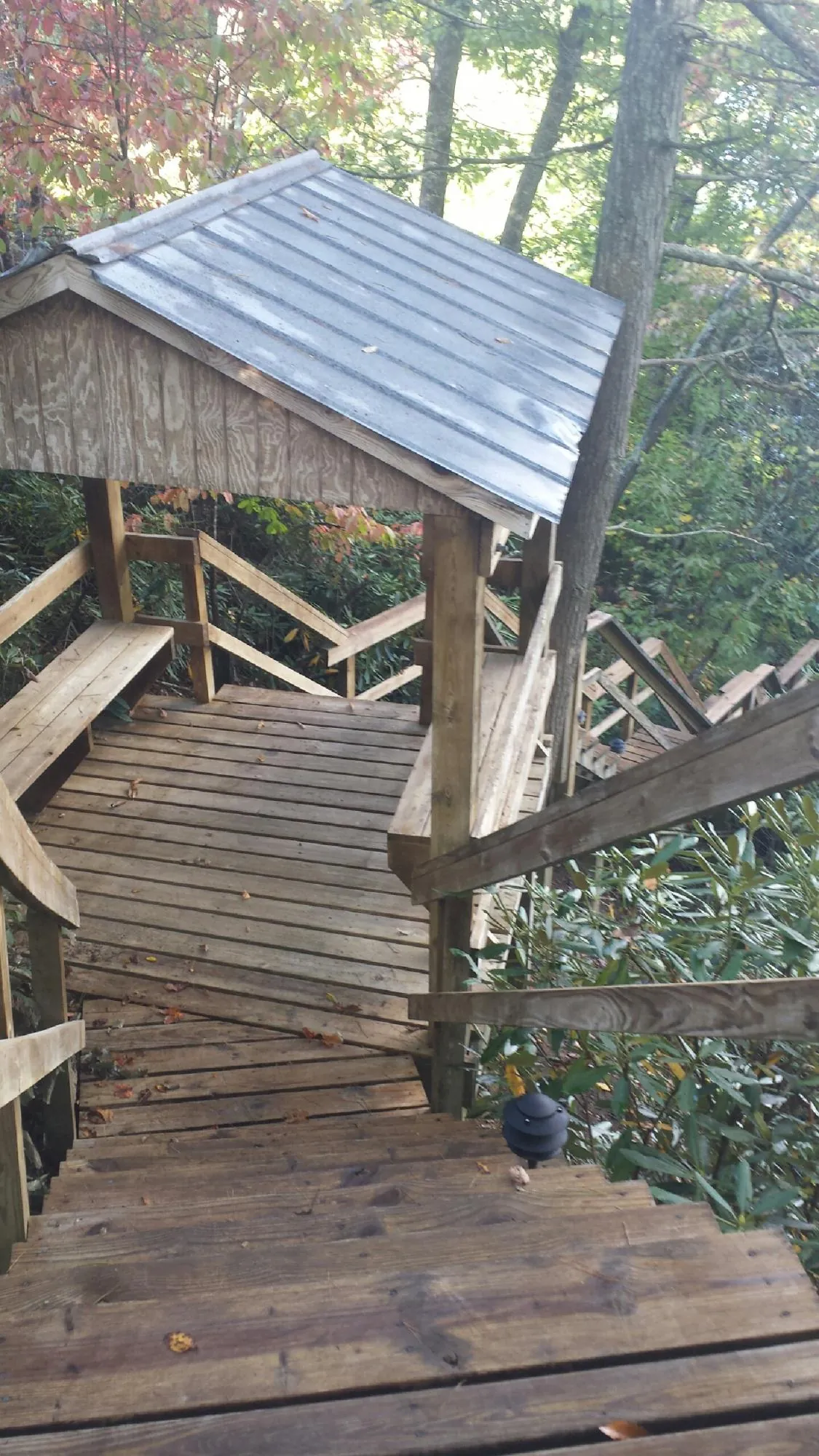 Metal roofed shelter over wooden steps on a wooded walkway — Skylight Repair & Installation work by our crew in Ganado