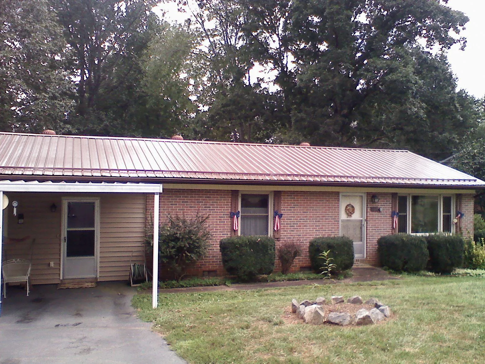Bronze metal roof and carport on a brick ranch home — Roof Repair work by our crew in Ganado