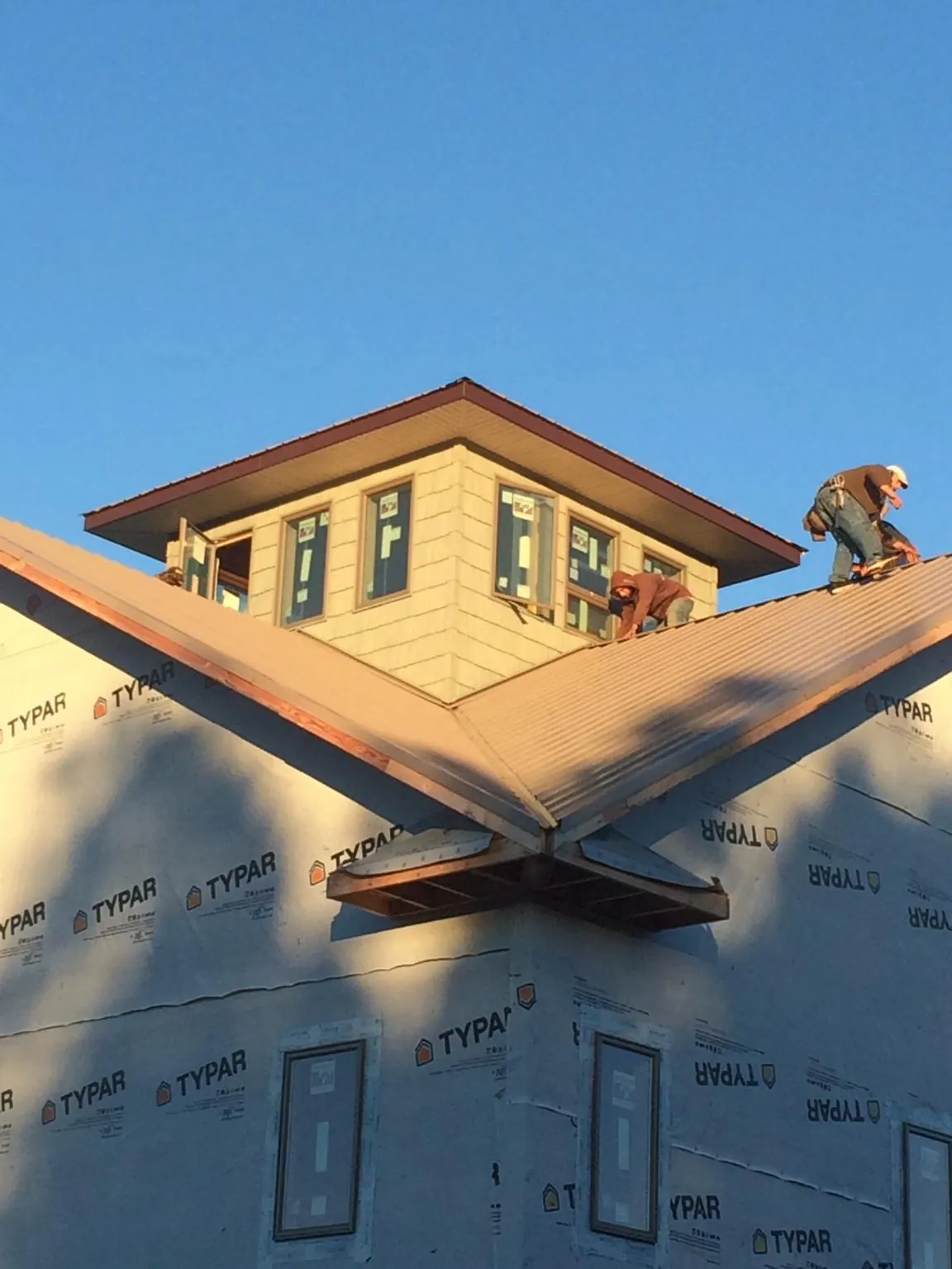 Roofers working around a rooftop cupola on a new metal roof at sunset — Roof Waterproofing in Ganado by Roofing Brothers
